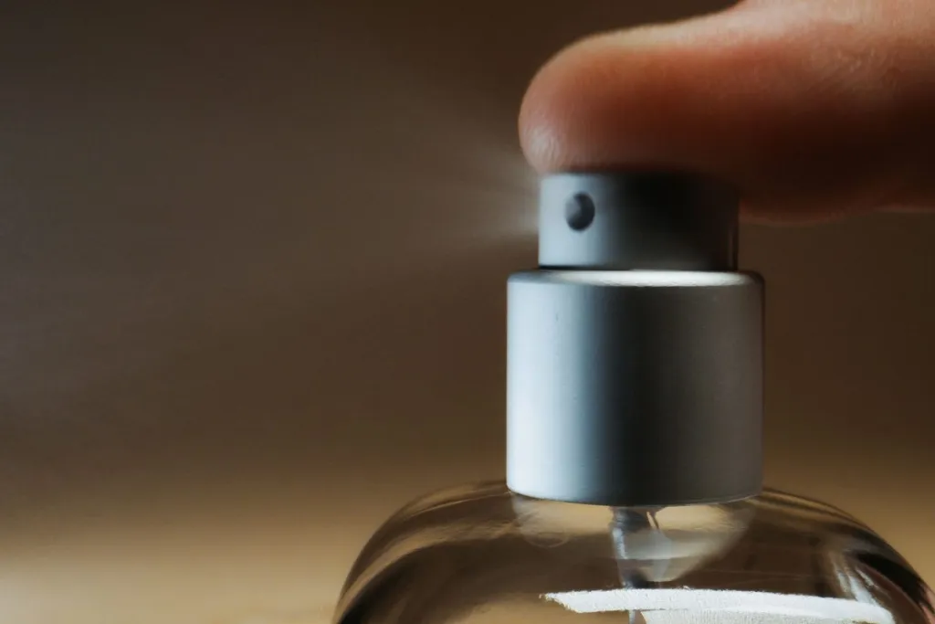 Finger pressing a perfume atomiser